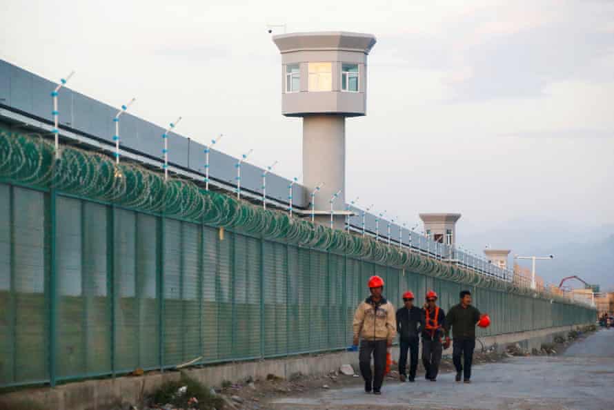 Des travailleurs passent devant la clôture d'enceinte de ce qui est officiellement connu comme un centre de formation professionnelle dans la région autonome ouïghoure du Xinjiang en Chine, le 4 septembre 2018.