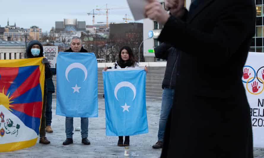Trois manifestants tiennent des drapeaux alors que quelqu'un passe 